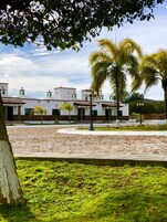 Un patio con un edificio blanco que destaca por sus techos de tejas rojas y detalles verdes.