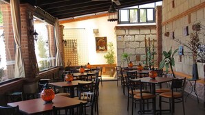 An indoor restaurant with brick walls, tiled floors, and tables with chairs. - Hotel Villas Mahando (Ezequiel Montes)