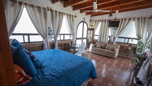 A bedroom with a large bed, a sofa, a small table, and a TV. - Hotel Villas Mahando (Ezequiel Montes)