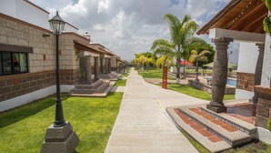 A pathway leading to a building with a tiled entrance and a covered area with columns. - Hotel Villas Mahando (Ezequiel Montes)