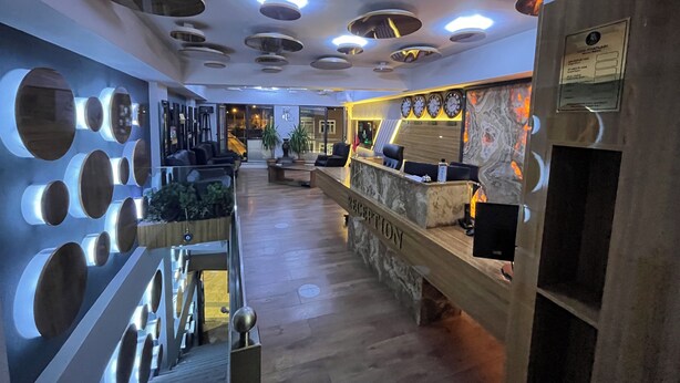 Un área de recepción con mostrador de mármol, varios relojes y un diseño moderno de techo.