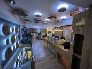 Un área de recepción con mostrador de mármol, varios relojes y un diseño moderno de techo.