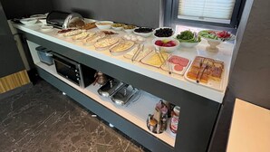 Una barra de buffet con diversos alimentos y un microondas.