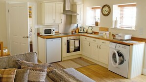 Une cuisine compacte avec des meubles blancs, un four à micro-ondes, un grille-pain, une bouilloire et un lave-linge.