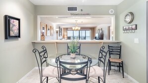Un coin repas comprenant une table ronde en verre, quatre chaises, un lustre et une plante en pot.