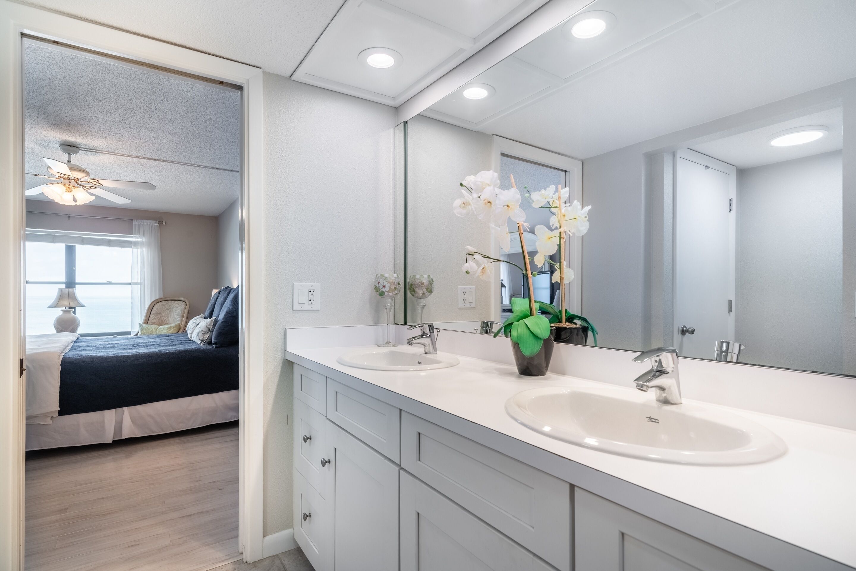Un bagno moderno con due lavabi, uno specchio grande e una ventola a soffitto.