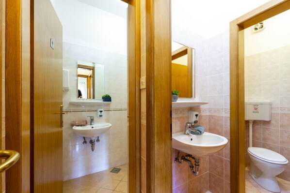 A bathroom with two sinks, a toilet, and a mirror.