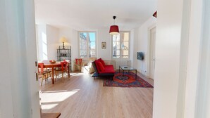 Ein geräumiger Wohnbereich mit Esstisch, Stühlen, einer Couch und einem Fernseher.