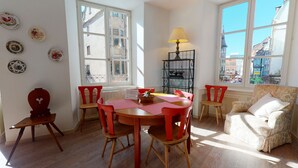 Ein Zimmer mit Holztisch, roten Stühlen, einem Korbwannen und einer Lampe.