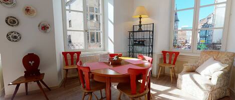 Una habitación con una mesa de madera, sillas rojas, una cesta de mimbre y una lámpara.