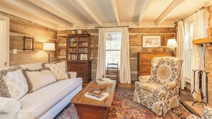 A cozy log cabin interior with a sofa, armchair, wooden coffee table, and a patterned rug. - The Holly House at Green Frog Farm (Alamo)