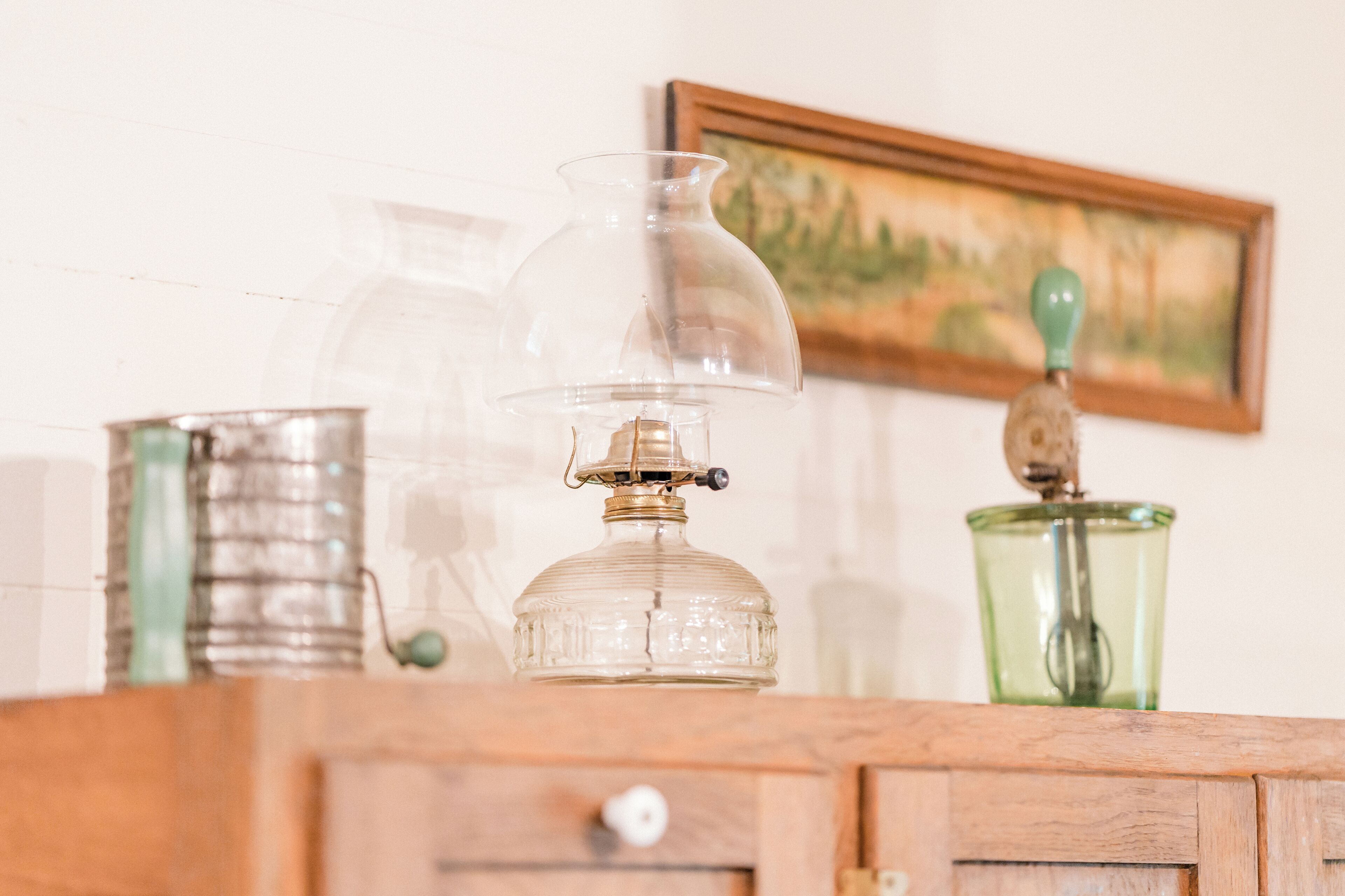 A wooden cabinet with a clear glass bottle and a green glass container on top.