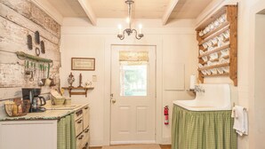A kitchen with wooden cabinets, a coffee maker, and a sink. - The Holly House at Green Frog Farm (Alamo)