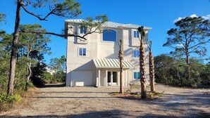 A two-story house with a flat roof, a front porch, and a driveway.