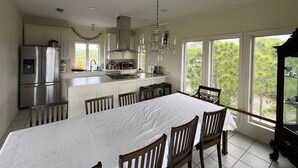 A modern kitchen with a dining area, large windows, and a chandelier.