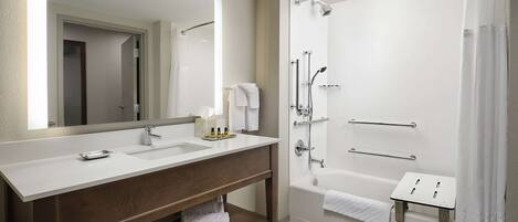 Une salle de bain moderne avec un meuble-lavabo à deux vasques, un grand miroir, une douche avec une porte en verre et un porte-serviettes.