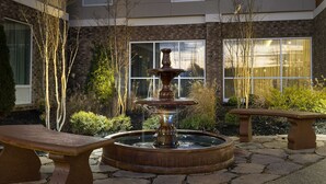 A courtyard with a central fountain, benches, and a building with large windows. - Best Western Plus Desoto (Olive Branch)