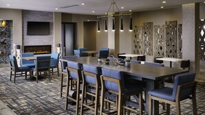 A modern hotel lobby with a bar area, seating, a fireplace, and a decorative wall. - Best Western Plus Desoto (Olive Branch)