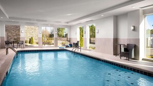 An indoor swimming pool with clear blue water, surrounded by lounge chairs and a stone wall. - Best Western Plus Desoto (Olive Branch)
