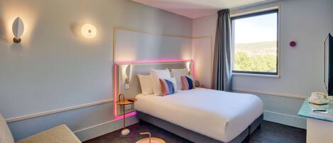 Una habitación de hotel moderna con una cama grande, una mesita de noche y una pequeña mesa redonda.