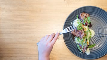 A hand holding a fork over a plate with food.