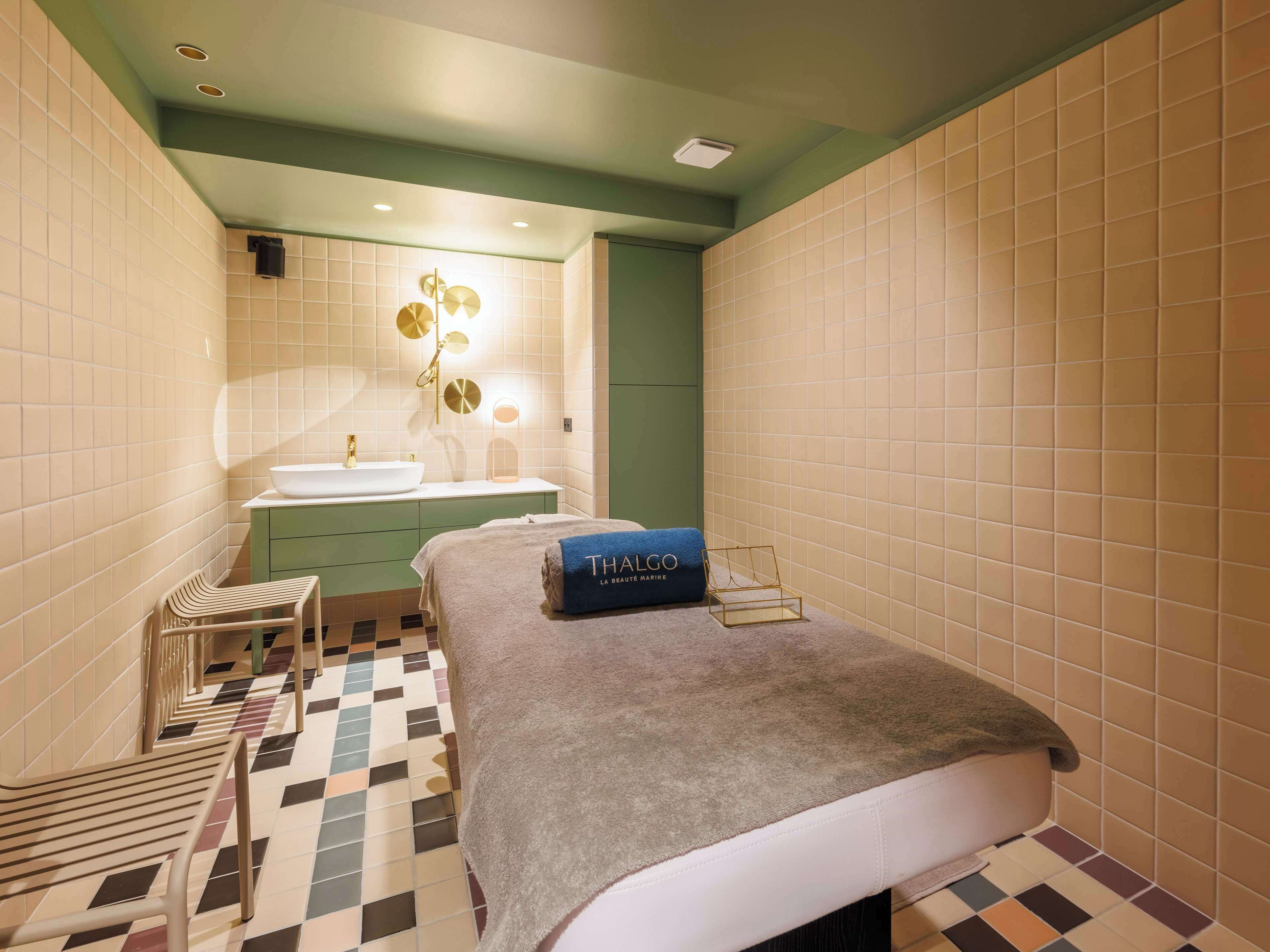 A hotel room with a bed, a small seating area, a vanity with a mirror, and a sink.