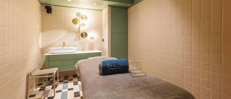 A hotel room with a bed, a small seating area, a vanity with a mirror, and a sink.