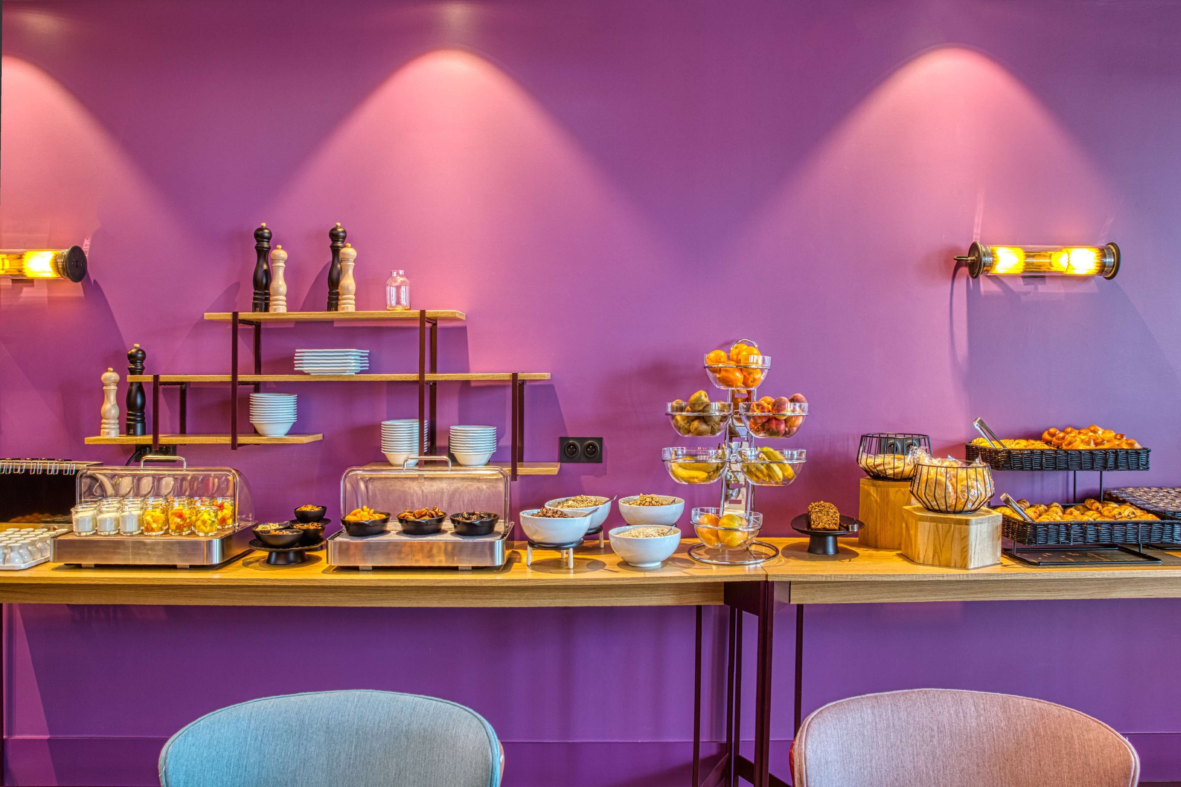 A buffet setup with various food items and a purple wall.