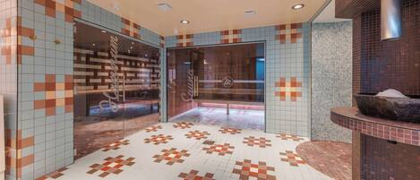 A modern lobby with patterned tile floors and walls, a reception desk, and a stone basin.
