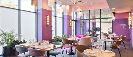 A modern restaurant interior with tables, chairs, and hanging pendant lights.