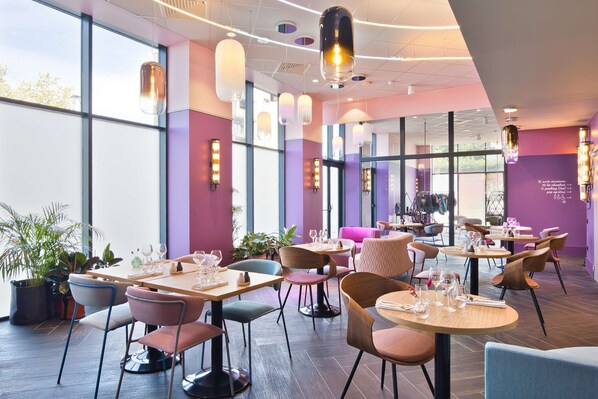 A modern restaurant interior with tables, chairs, and hanging pendant lights.