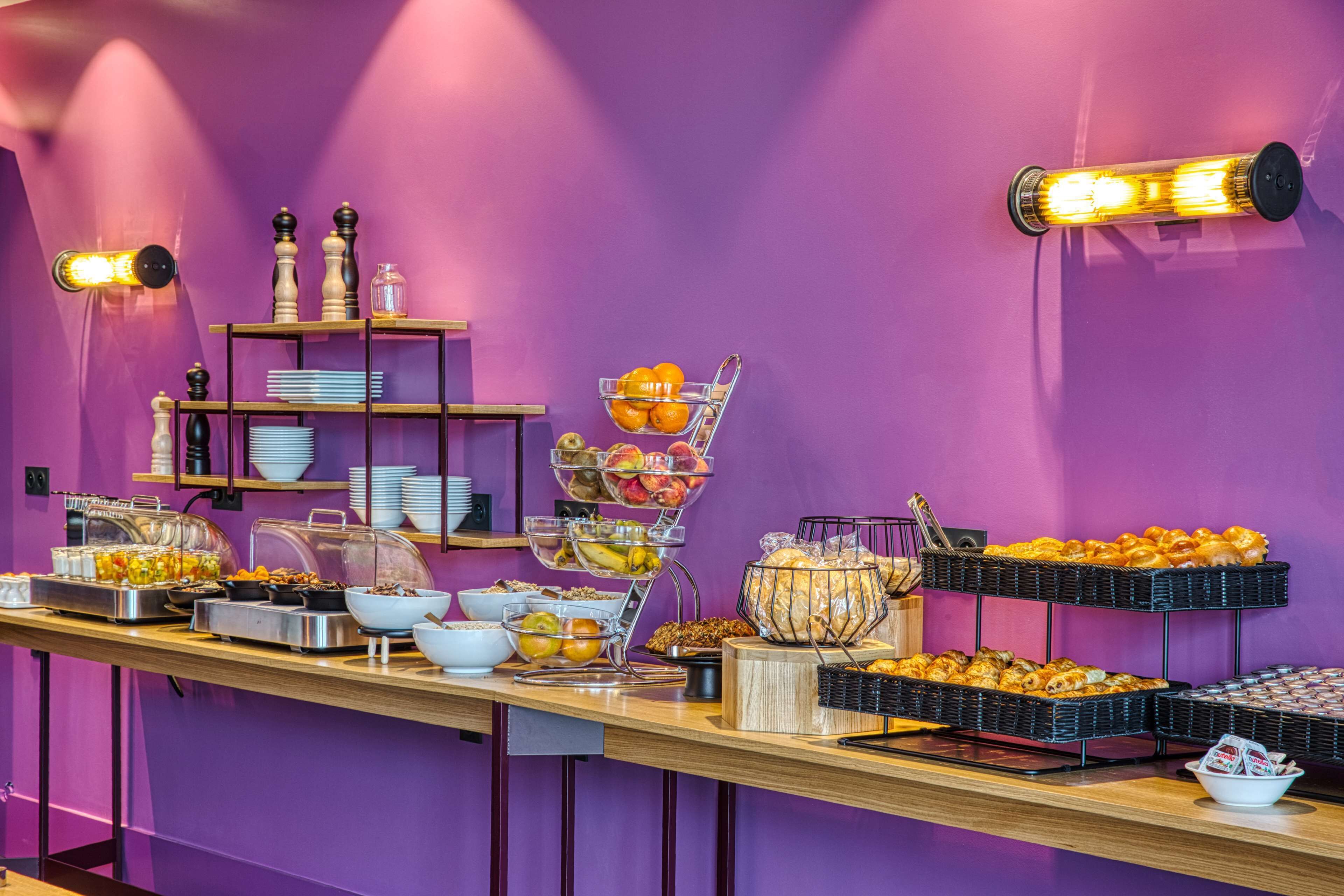 A buffet with various food items and a purple wall.