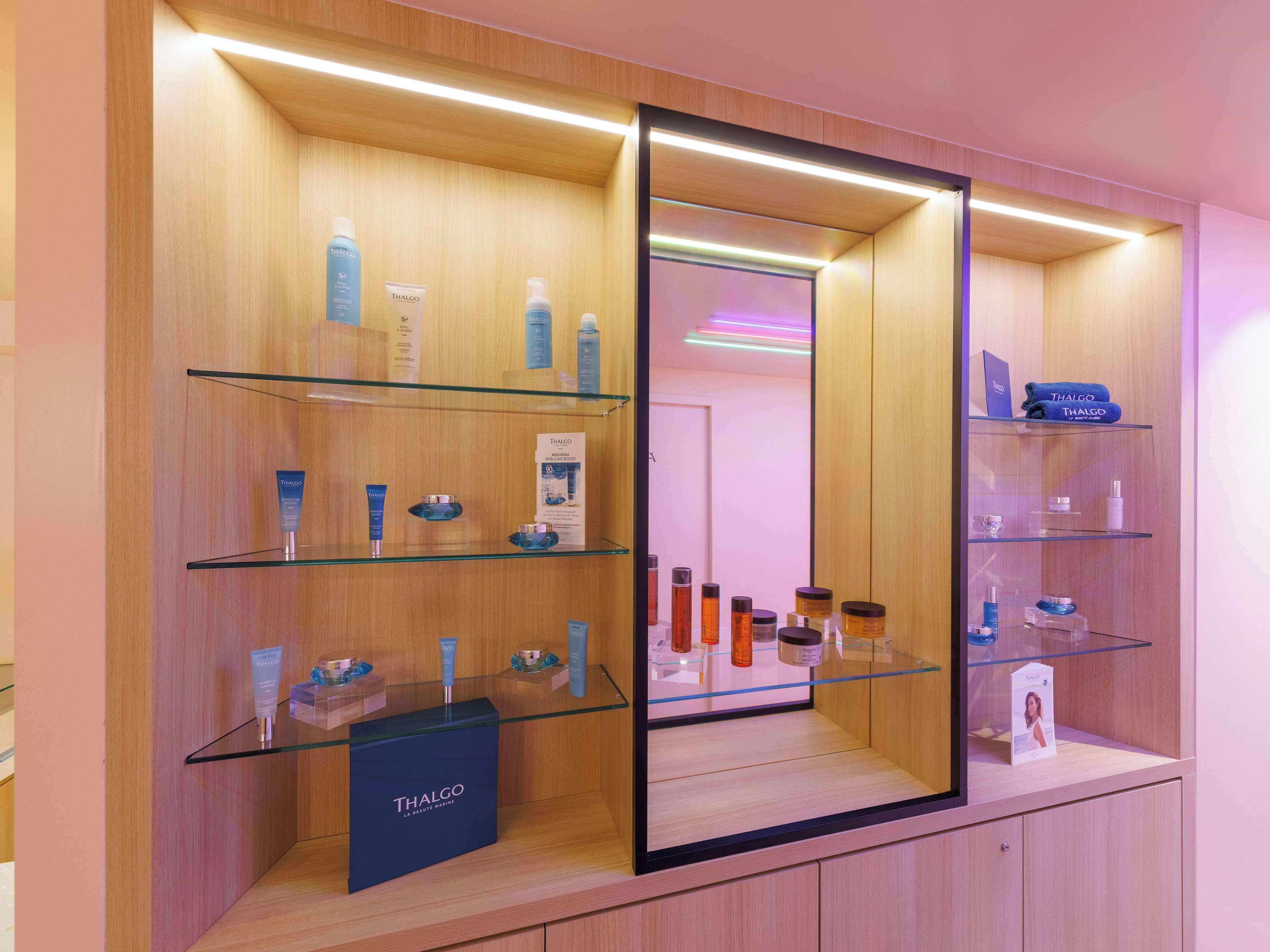 A Thalgo beauty salon with glass display shelves and a large mirror.