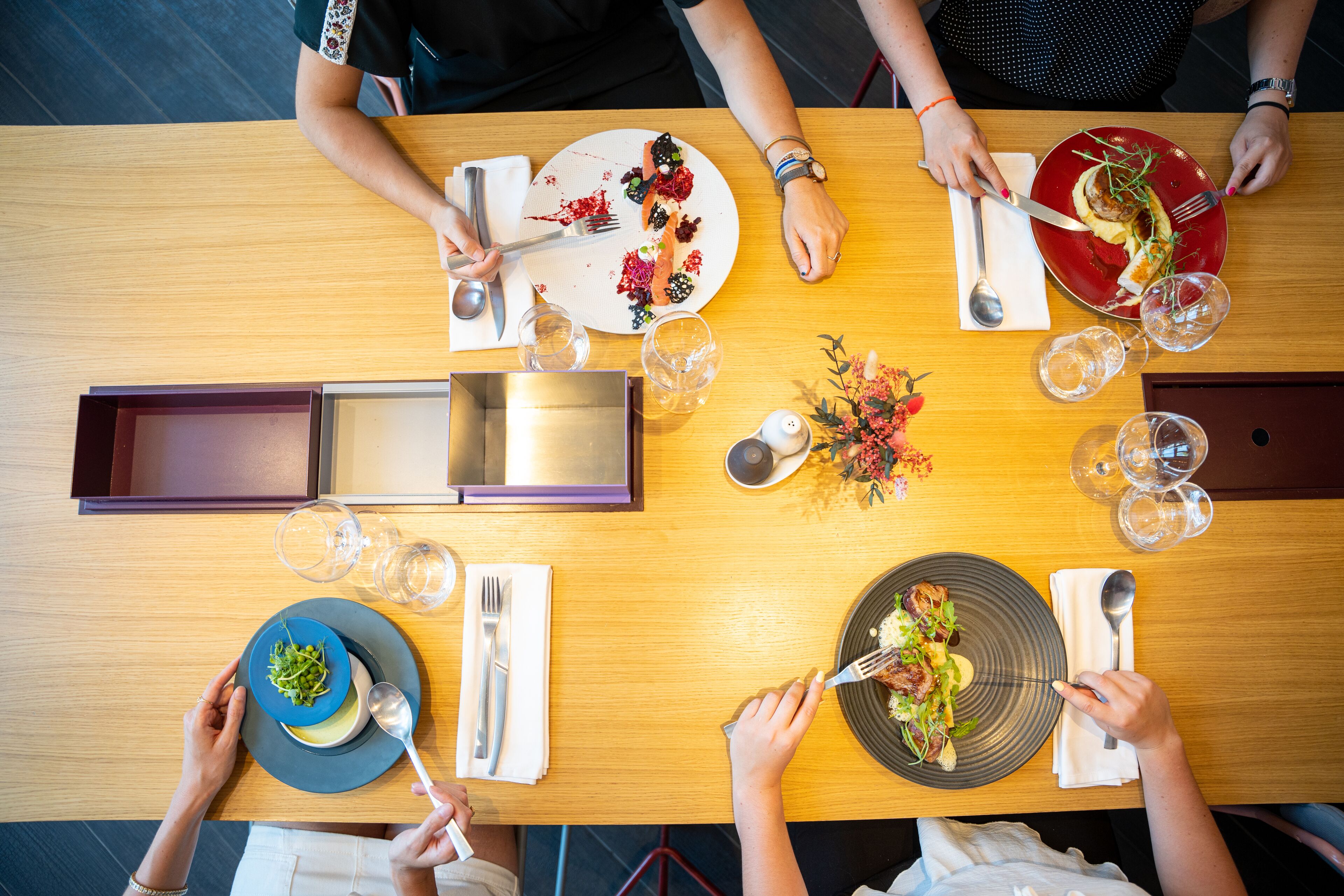 Una mesa de comedor con varios platos de comida, cubiertos y vasos.