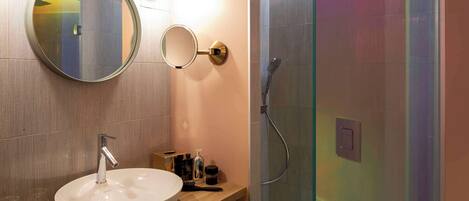 A bathroom with a round mirror, a sink, and a shower.