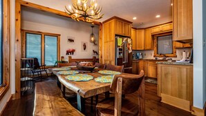 A dining area with a wooden table and benches, surrounded by wooden cabinets and a chandelier. - 2BR, 2BA Log Cabin (Nashville)