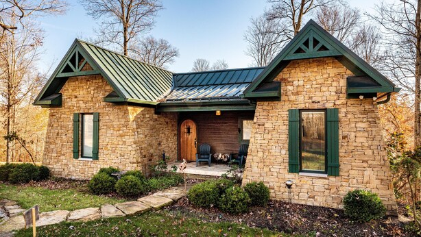 A stone house with a green roof and a wooden door. - 2BR, 2BA Log Cabin (Nashville)