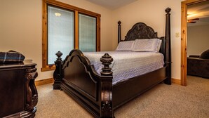 A bedroom with a four-poster bed, a wooden headboard, a window with blinds, and a carpeted floor. - 2BR, 2BA Log Cabin (Nashville)
