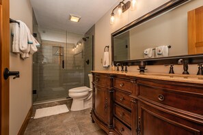 A bathroom with a wooden vanity, a large mirror, and a glass shower enclosure.