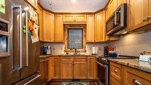 A kitchen with wooden cabinets, stainless steel appliances, and a window above the sink. - 2BR, 2BA Log Cabin (Nashville)