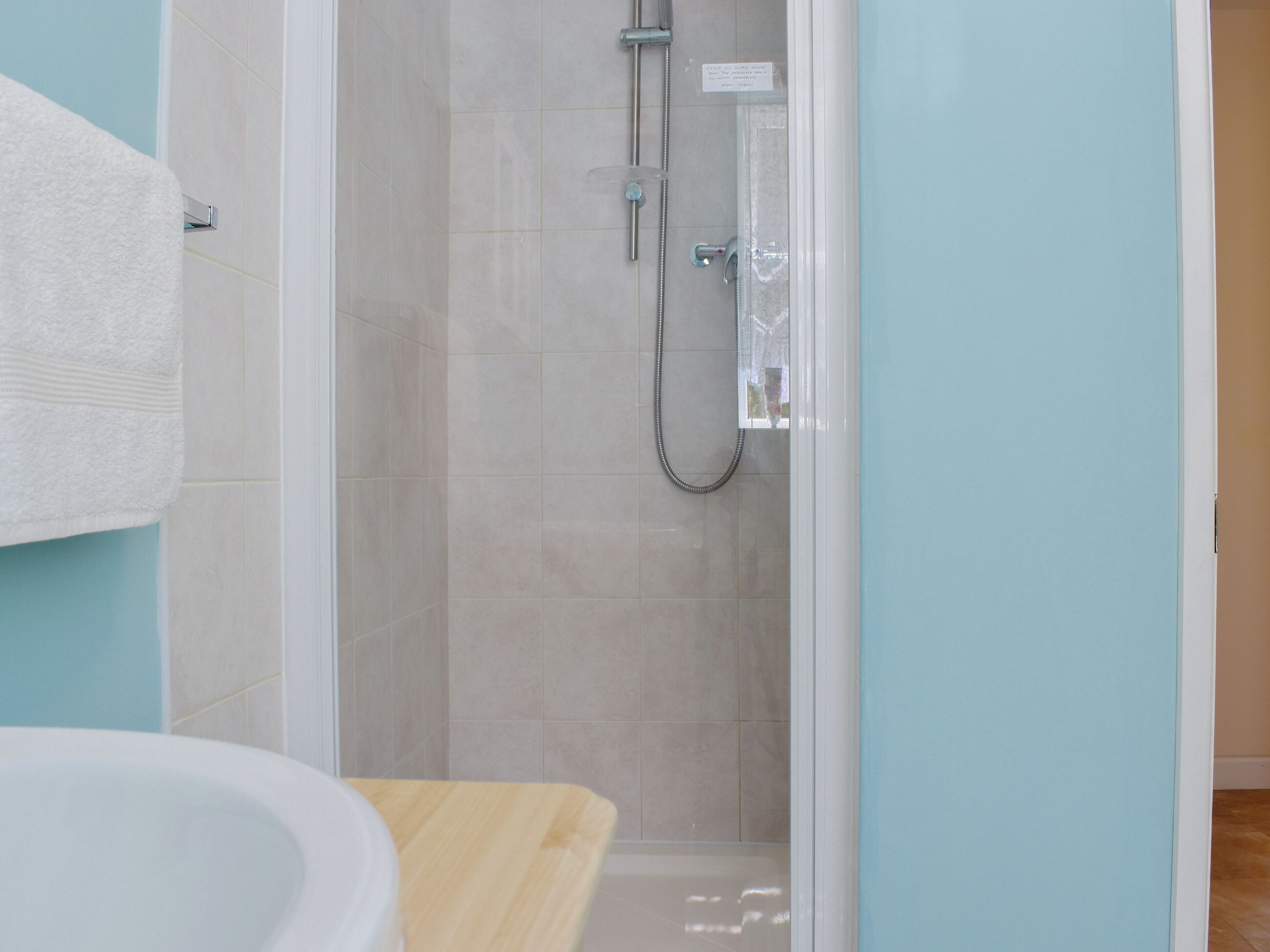 A bathroom with a shower, a sink, and a towel rack.