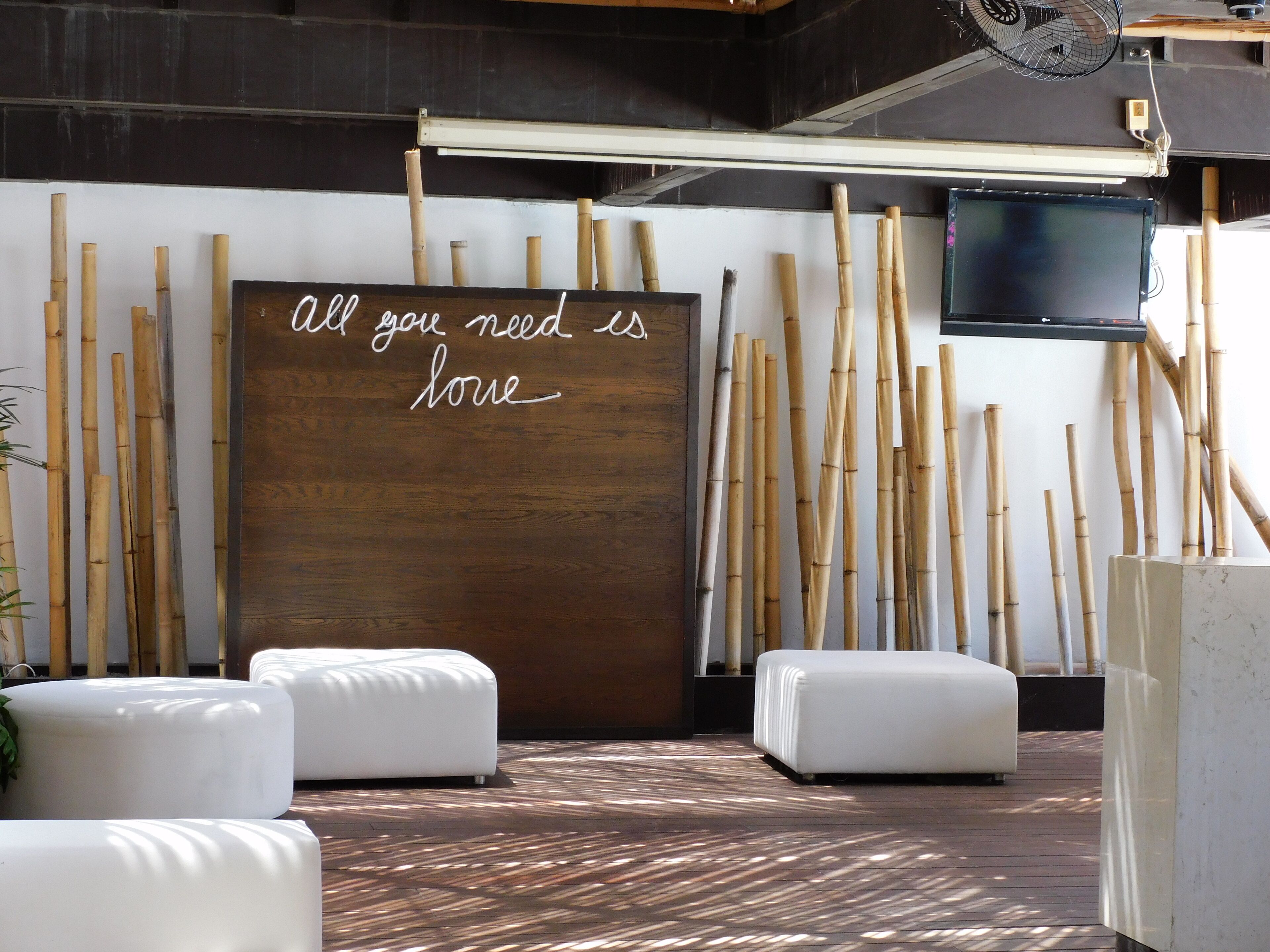 A modern interior with a wooden wall and bamboo sticks, white cushioned seating, and a motivational quote.