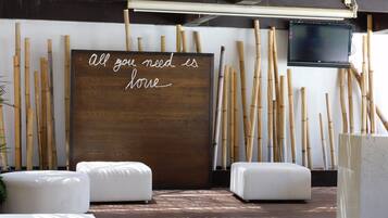 A modern interior with a wooden wall and bamboo sticks, white cushioned seating, and a motivational quote.