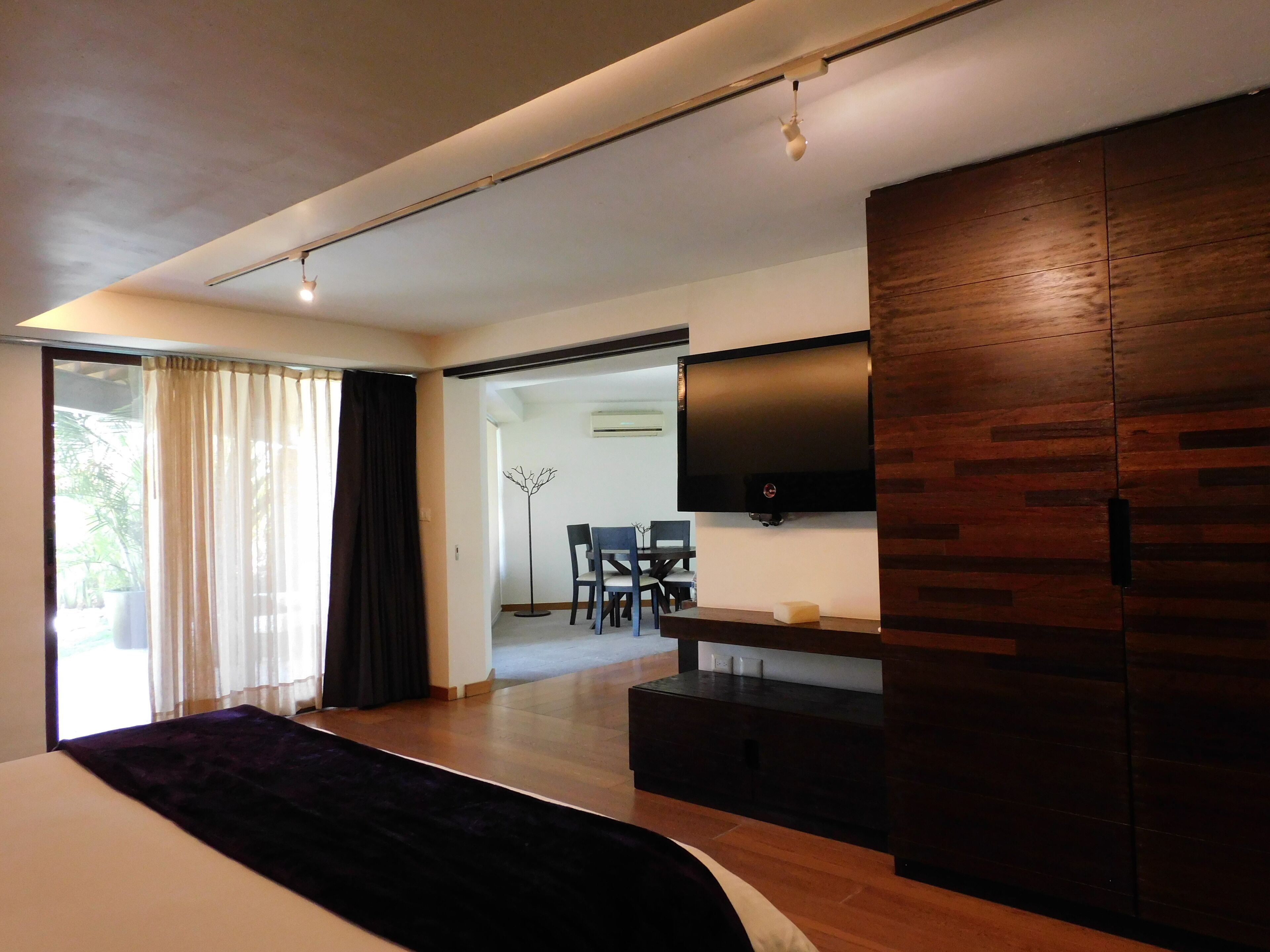 A modern bedroom with a large bed, a TV mounted on the wall, and a wooden wardrobe.