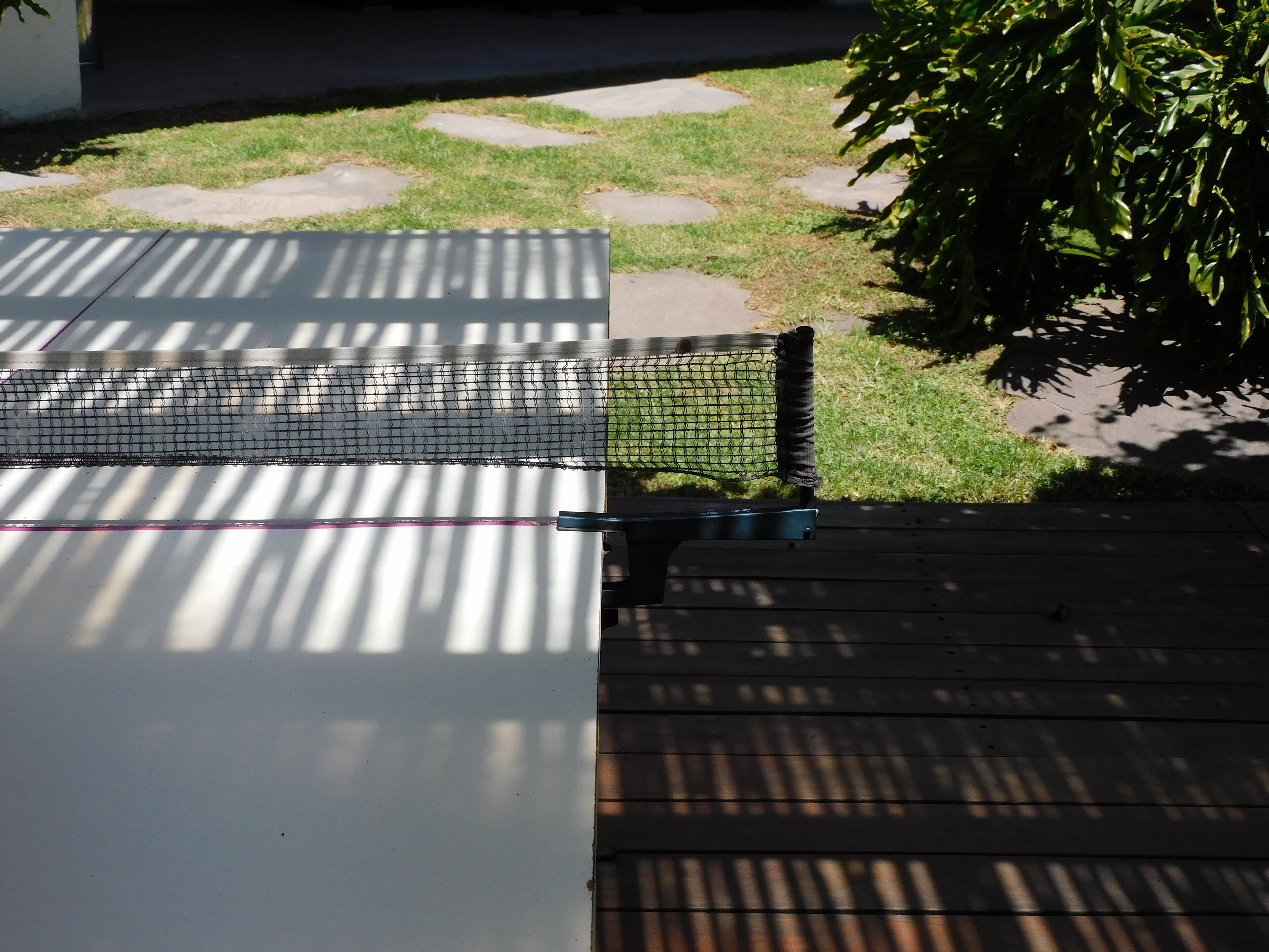 Una terraza de madera con un área cercada con red, posiblemente para actividades al aire libre.