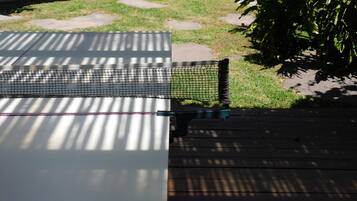 Una terraza de madera con un área cercada con red, posiblemente para actividades al aire libre.
