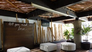 A modern room with a wooden floor, white cushioned seating, a bamboo wall, and a motivational quote. - Hotel & Spa Luna Canela Boutique (Atlixco)