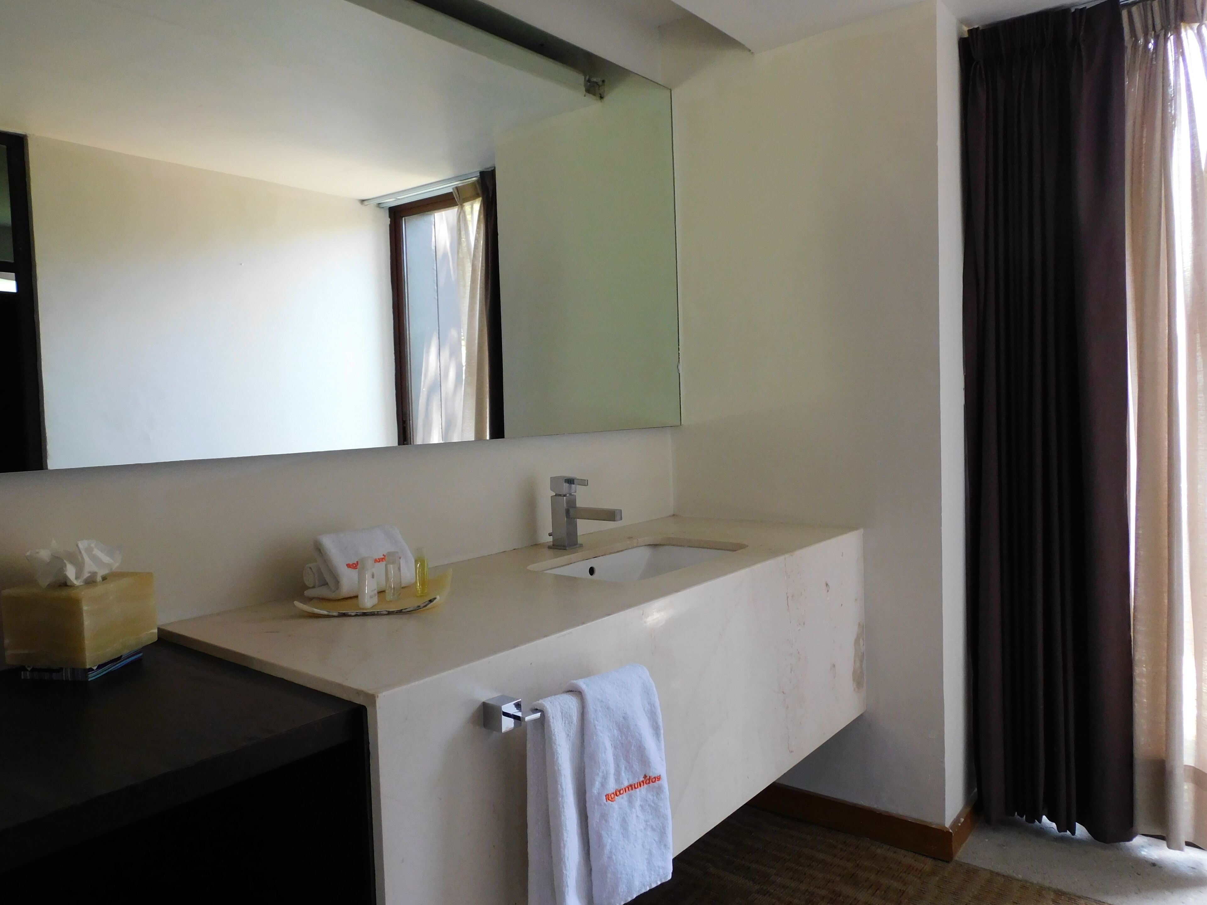 Une salle de bain d  ’hôtel avec un grand miroir, un lavabo et un porte-serviettes.