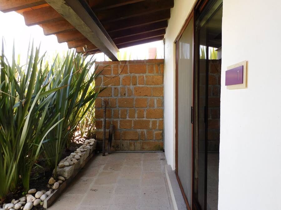 A covered outdoor area with a stone wall, a tiled floor, and a door with a purple sign.