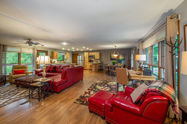 A spacious living room with a red sofa, a dining area, and a kitchen.